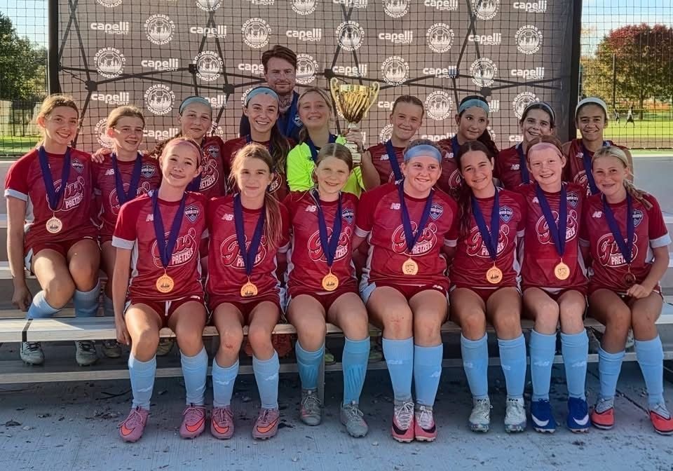 River City FC team in maroon away kits celebrating with medals and a trophy
